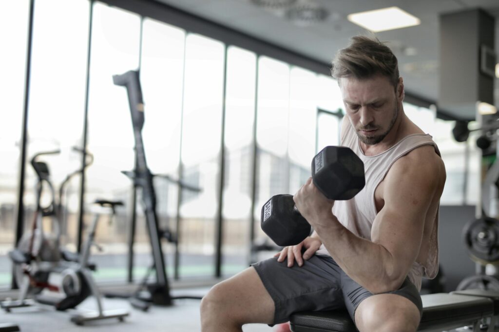 Ein Mann mit Muskeln trainiert im Fitnessstudio. Er verwendet ein veganes Proteinpullver für seinen Muskelaufbau.